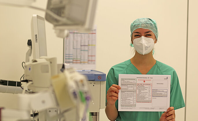 Anästhesietechnische Assistentin hält OP-Checkliste in die Kamera. 