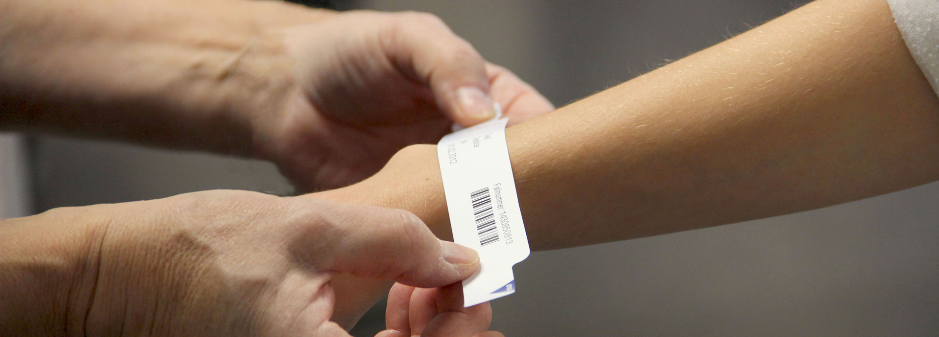 Patientenarmband wird am Handgelenk einer Patientin befestigt