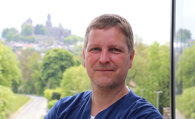 Portrait von Dr. Hagen Maxeiner, Chefarzt Stationäre Schmerztherapie. Im Hintergrund ist das Braunfelser Schloss zu sehen. 