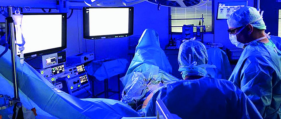 Dr. Frank Ulrich bei einer Operation im OP-Saal. Im Saal ist blaues Licht an. 