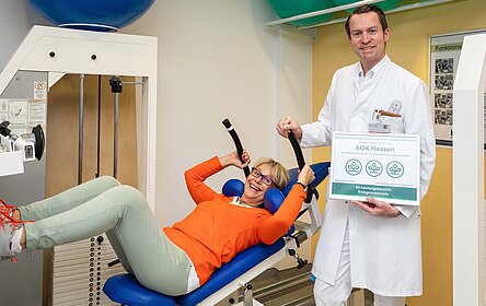 Chefarzt PD Dr. René Burchard freut sich über die Auszeichnung, während Patientin Kerstin Schüler-Melbaum aus Dietzhölztal bereits zwei Wochen nach künstlichem Kniegelenk nahezu beschwerdefrei Gewichte stemmt.