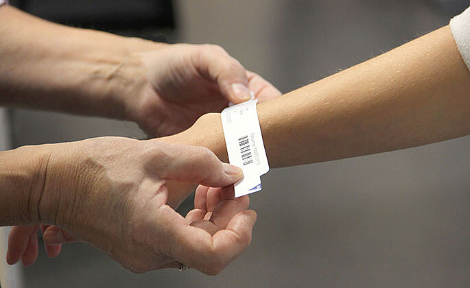 Patientenarmband wird am Handgelenk einer Patientin befestigt