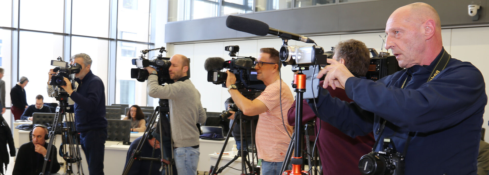Journalisten mit Mikrofons und Kameras bei einer Pressekonferenz. 