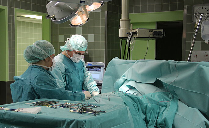 Zwei Mitarbeiter operieren einen Patienten. 