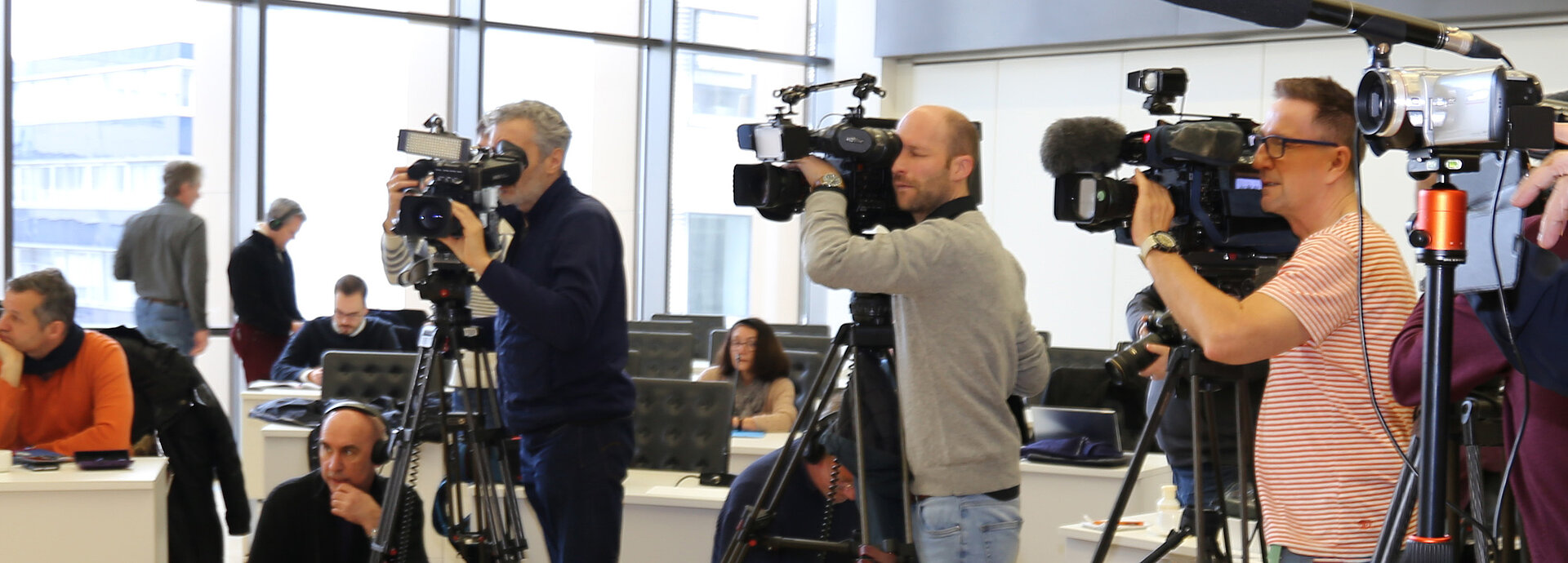 Journalisten mit Mikrofons und Kameras bei einer Pressekonferenz. 